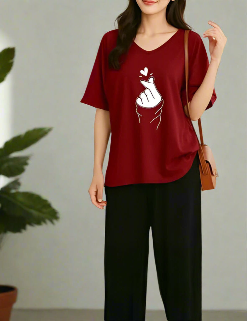 Woman wearing a red t-shirt with a white graphic design, standing indoors next to a plant.